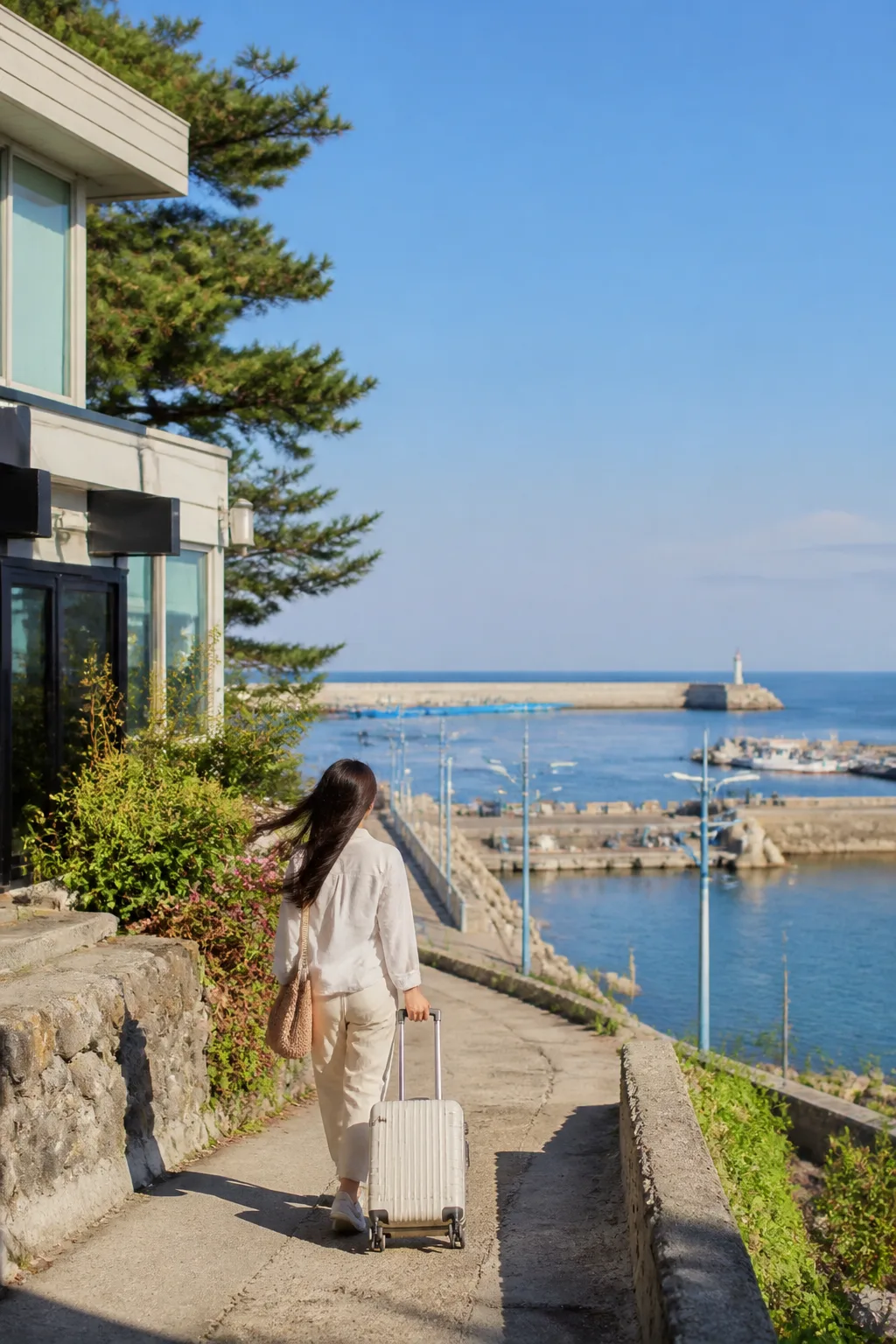 바람 부는 묵호 항구와 해안 산책로를 바라보며 이동하는 여행객과 묵호숙소 여행 풍경